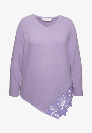 Lilla langærmet bluse med V-udskæring, der har en asymmetrisk kant og blonde detaljer på den ene side. Blød tekstur, minimalistisk design.