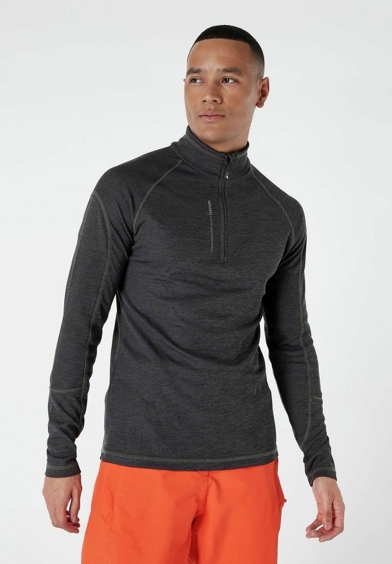 Maglia nera a maniche lunghe con zip al collo, con una finitura testurizzata e cuciture a contrasto; indossata con pantaloni corti arancioni, dal taglio aderente.