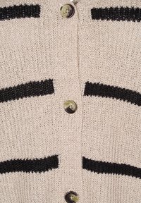 Bež pravljena cardigan s črnimi vodoravnimi črtami, ki ima velike okrogle gumbe in teksturirano, odprto tkanino.