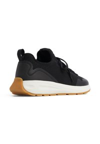 Sneaker noir avec une tige en mesh et cuir, semelle en caoutchouc et une semelle extérieure en gomme contrastante. Comprend des lacets et une languette au talon.