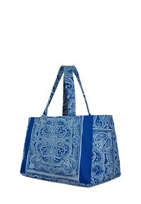 Niebieska torba na ramię z wzorem paisley w kolorze białym. Posiada dwa długie uchwyty i strukturalny kształt. Wykonana z trwałego materiału.