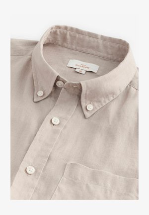 Light beige linen shirt with a button-down collar, featuring white buttons, a chest pocket, and a tag labeled "NEXT SIGNATURE M."