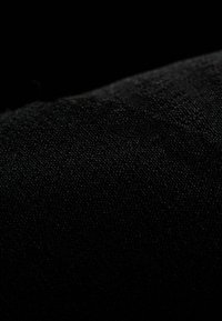 Zwarte stoffen textuur met een fijne weefsel, toont subtiele variaties in licht en schaduw over het oppervlak. Geen patronen of accenten zichtbaar.