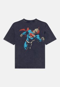 Mörkgrå bomullströja med Superman-tryck i blått och rött. Kortsleeve, rundhalsad, avslappnad passform med sliten textur.