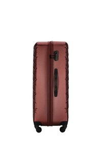 Valigia rigida di un elegante borgogna metallizzato, caratterizzata da una superficie testurizzata, una cerniera nera e un manico retrattile, con quattro ruote per la mobilità.