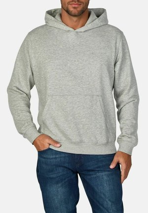 Hellgrauer Hoodie aus weichem Stoff, mit einer Kängurutasche, Kapuze mit Kordelzug und gerippten Bündchen. Kombiniert mit dunklen Jeans.