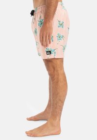 Rosa Badehose mit floralem Muster, blauen Blumen, elastischem Bund und schwarzem Markenlogo-Patch am linken Bein.