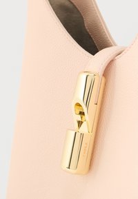 Τσάντα χειρός από ανοιχτό ροζ δέρμα με κούμπωμα από χρυσό μέταλλο. Η υφή είναι λεία, με στρογγυλεμένο σχήμα και λεπτομέρεια πλαϊνής ραφής.