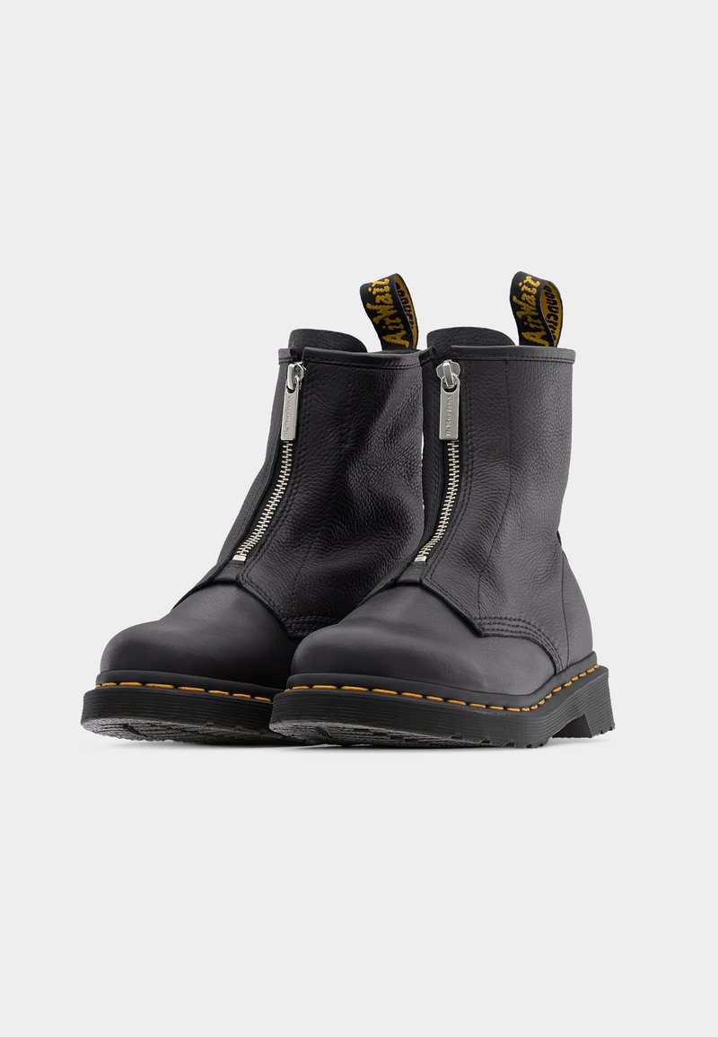 Zwarte leren enkellaarsjes met ritsen aan de voorkant, gele stiksels en lusvormige treklussen. Stevige zolen met een gestructureerde afwerking.