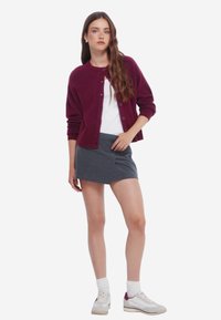 Burgundská cardigan s knoflíky, bílý tričko, šedá mini sukně, bílé ponožky a světle tenisky s burgundskými akcenty. Neformální outfit.