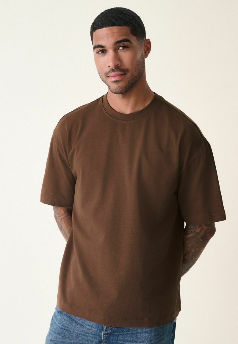 Brun bomulds T-shirt med rund hals, korte ærmer og en afslappet pasform. Har en glat tekstur og et minimalistisk design.