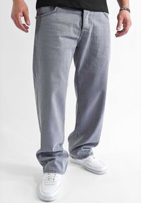 Light gray denim jeans with a relaxed fit, featuring front pockets and subtle fading, paired with white sneakers.