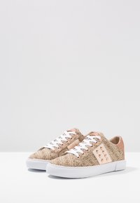 Béžové tenisky s vzorem z texturované látky, bílé tkaničky a bílá gumová podrážka. Výrazné růžově zlaté detaily na bocích.
