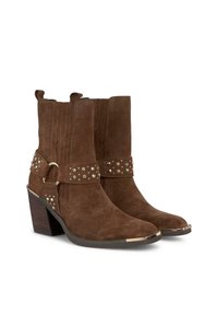 Bottines en daim marron avec une ceinture décorative, des clous argentés, un talon carré et une pointe effilée ; dotées de deux tirants pour un enfilage facile.