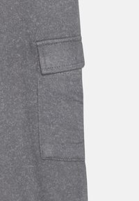 Gray fabric featuring a patch pocket with visible stitching. The surface has a textured appearance, suggesting a soft, casual material.