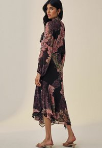 Rochie midi neagră cu motive florale, cu mâneci lungi, având modele roz și verzi. Fabrică ușoară și vaporasă, cu un tiv ondulat.