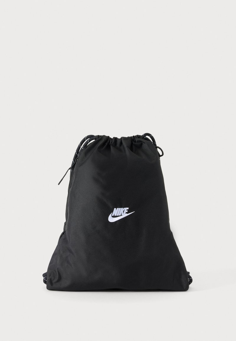 Μαύρη τσάντα Nike με κορδόνι και λευκό λογότυπο στο κέντρο σε απλό ανοιχτό φόντο.