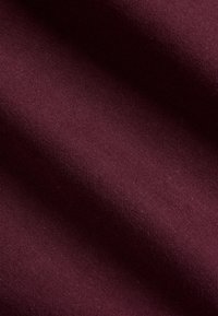 Burgundy färg som har en slät textur, med ett subtilt vävmönster. Materialet ser hållbart ut och har en något lyster.