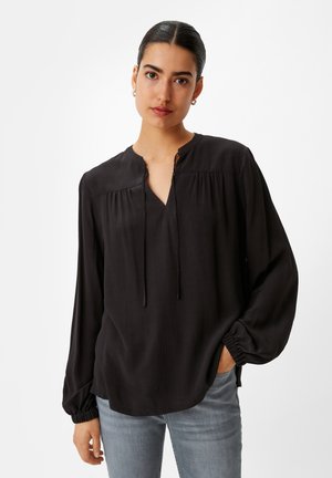 Schwarze Bluse mit langen Ärmeln und Schlüssellochausschnitt, gerafften Details an den Schultern und elastischen Bündchen. Glatte Textur, lockere Passform.