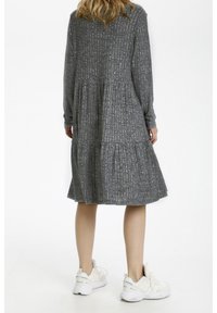 Grijze lange mouw jurk met een textuur rib patroon, tiered rok en ronde halslijn, gecombineerd met witte sportieve sneakers.