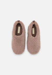 Fuzzy slippers in soft beige material with a plush texture, low-cut design, and a small loop at the heel for easy wear.