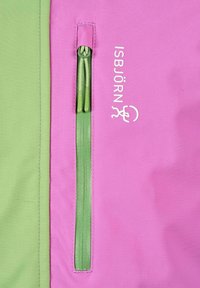 Vihreä vetoketju, jossa on kaksi vetopuljinta, vaaleanpunaisella ja vihreällä kankaisella paneelilla, valkoisen ISBJÖRN-brändin nimen ja logon vieressä vaaleanpunaisella kankaalla.