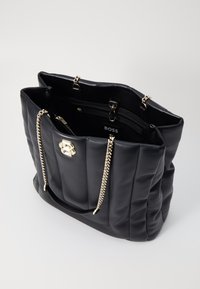 Mala tote de pele sintética acolchoada preta com ferragens douradas, apresentando uma alça de corrente e um bolso com fecho interior. Logótipo visível no interior.