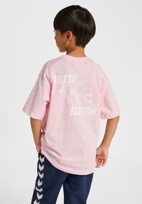 Rosa t-shirt med korta ärmar och en stor vit grafik på ryggen med texten "FRESH SEASON", som har en cirkulär design och lövaccents.