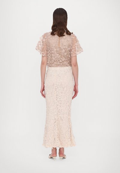 Kanten top met korte, gerimpelde mouwen in lichtbeige boven een aansluitende, lange kanten rok in bijpassende kleur, met florale patronen over de gehele rok.