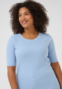 Camiseta de punto acanalado azul claro con mangas cortas y escote redondeado. Textura suave con detalles sutiles, diseño ajustado.