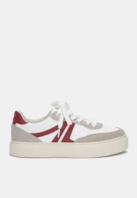 Weiße und graue Sneakers mit roten Akzenten, ausgestattet mit einem glatten Leder-Obermaterial, strukturierten Wildlederelementen und einer dicken Gummisohle.