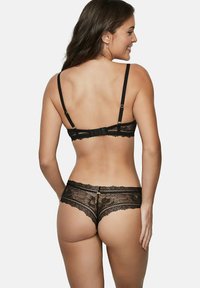 Ensemble de lingerie en dentelle noire comprenant un soutien-gorge avec des bretelles ajustables et une fermeture à crochets, accompagné d'une culotte en dentelle assortie avec des motifs floraux.