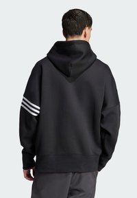 Černá mikina s velkou kapucí, která má bezešvý design a tři bílé pruhy na levém rukávu. Měkká, texturovaná tkanina.