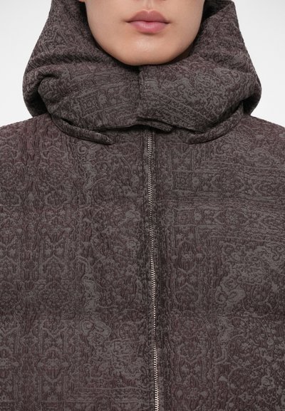 Hooded jaka tumšā burgundu krāsā ar strukturētu rakstu. Aprīkota ar priekšējo rāvējslēdzēju un cieši pieguļošu kapuci.