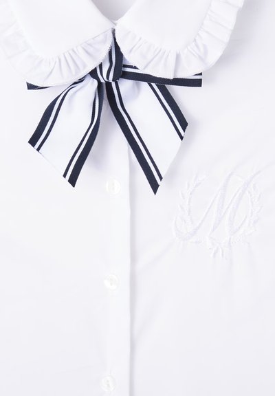 Camicia bianca con colletto arricciato, cravatta a farfalla a righe navy e accento ricamato con "M" circondato da un motivo di ghirlanda floreale.