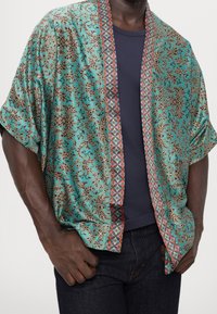 Silke kimono-jakke med en teal base og intrikate brune blomsterdesigns, kantet af en geometrisk rød og brun trim. Korte ærmer og afslappet pasform.
