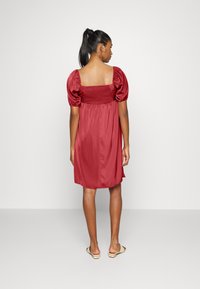 Vestido vermelho com decote quadrado, mangas bufantes e corpete franzido. Tecido suave e sedoso com um corte solto que termina acima do joelho.