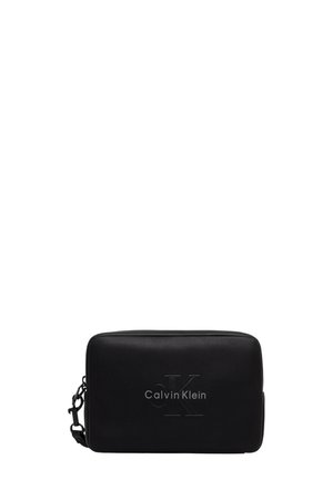 Pochette noire rectangulaire Calvin Klein avec logo CK embossé et bandoulière latérale amovible sur fond blanc uni.