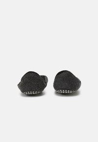 Pantofole grigie in feltro con una texture morbida, caratterizzate da una forma arrotondata e suole in gomma con pois bianchi per una buona aderenza. Nessun marchio o motivo visibile.