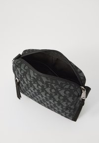 Black patterned fabric bag with a zip closure, featuring a smooth texture, sleek design, and a short strap on the side for easy carrying.