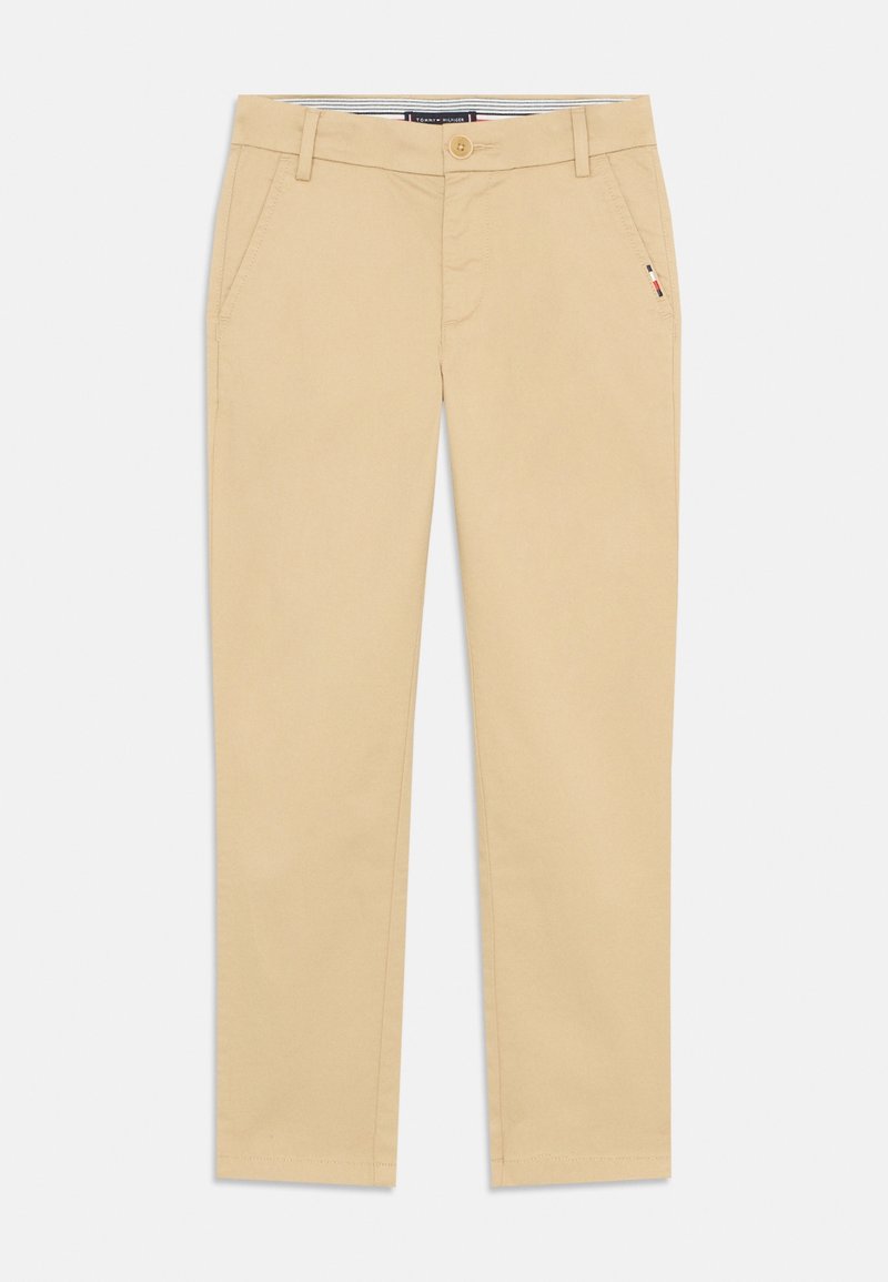 Pantalon beige slim fit avec poches avant, passants pour ceinture, fermeture par boutons et petit détail drapeau près de la poche droite.