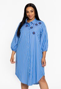 Blauw gestreepte jurk met een knoopsluiting aan de voorkant, korte puffmouwen en bloemversieringen op de borst. Gemaakt van lichtgewicht stof.
