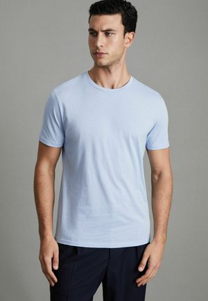 Tricou bleu deschis cu guler rotund, confecționat dintr-un material neted. Mâneci scurte, croială slim, design minimalist fără modele sau accente vizibile.
