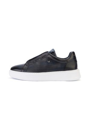 Zapatilla negra de cuero con suela blanca gruesa, diseño de corte bajo y detalles de costura mínimos mostrados de lado sobre un fondo blanco.
