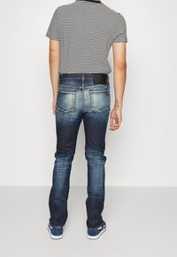 Jeans i denim med en urblekt blå finish, raka ben och bakfickor; kombinerat med en svartvit randig t-shirt.