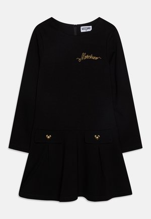 Robe noire à manches longues avec l'inscription Moschino dorée sur la poitrine, deux poches à rabat devant avec boutons ourson dorés et une jupe évasée.