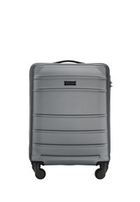 Grey hard-shell suitcase with horizontal ridges, featuring a telescopic handle and four black wheels for mobility. Logo displayed on the front.