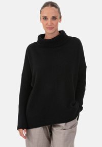 Pull noir surdimensionné à col roulé avec manches côtelées et coupe décontractée. Confectionné en maille douce, offrant une texture confortable.