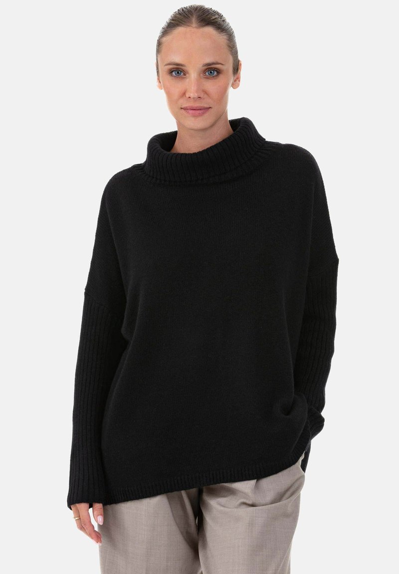 Pull noir surdimensionné à col roulé avec manches côtelées et coupe décontractée. Confectionné en maille douce, offrant une texture confortable.