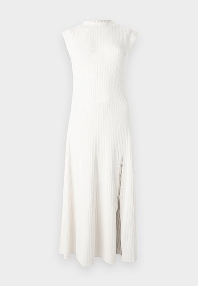 Robe midi blanche sans manches en maille côtelée, avec un col montant et une fente latérale ornée de détails en chaîne décorative.